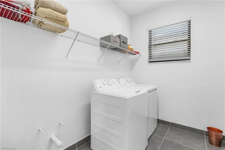 Second-floor laundry with pre-plumbed for future sink, upgraded tile floor, and shelving.