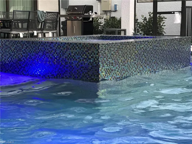 View of 360 waterfall spa and tile wall feature with color changing pool lighting