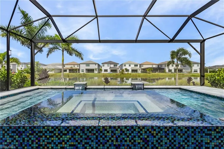 View of custom pool featuring a screened in lanai with picture window of lake view, large custom pool with 360 waterfall spa and light and water features