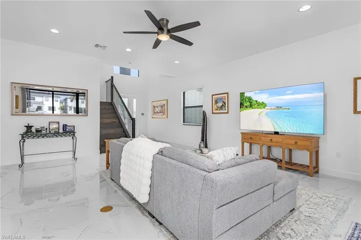 Open living room featuring light marble finish flooring, recessed lighting, stairway, and a ceiling fan