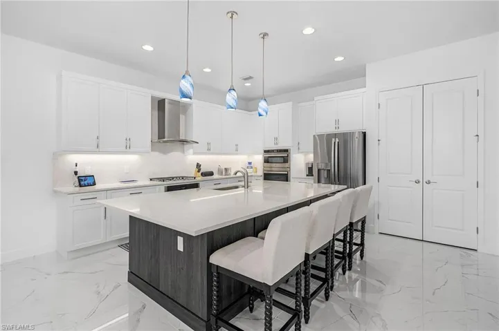 Kitchen fully outfitted with a top-of-the-line GE Profile stainless steel appliance package, premium quartz countertops, upgraded cabinetry, pantry, pendant lights and designer flooring throughout