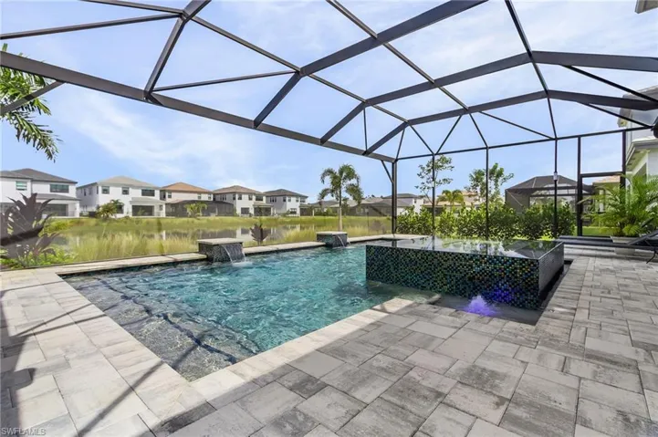 View of custom pool featuring a screened in lanai with picture window of lake view, large custom pool with 360 waterfall spa and light and water features