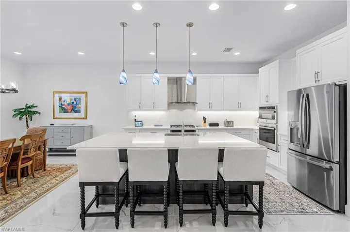 Gourmet Kitchen featuring stainless steel appliances, light marble finish flooring, a breakfast bar, and recessed lighting