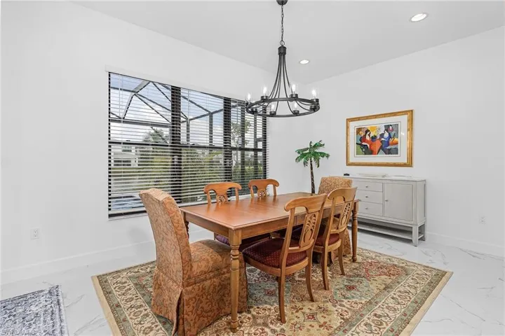 Dining area with light marble finish flooring, a chandelier, and recessed lighting