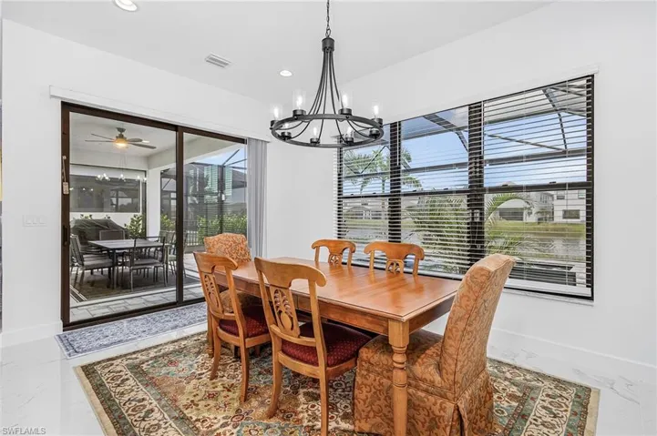 Dining room featuring a chandelier, recessed lighting, and marble look tile flooring with lake views
