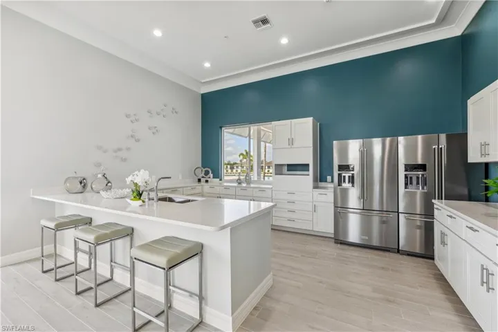 Kitchen with high end refrigerator, a sink, a breakfast bar, a peninsula, and white cabinets