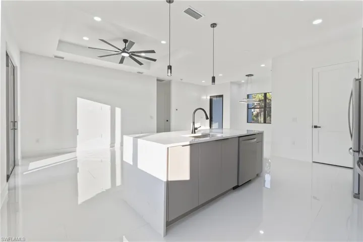 Kitchen featuring modern cabinets, gray cabinetry, pendant lighting, an island with sink, and stainless steel appliances