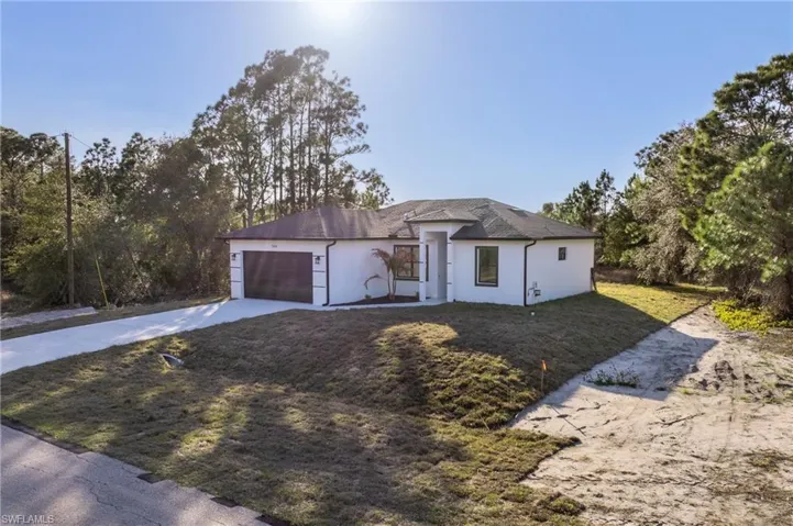 View of front of house with a garage, driveway, a front lawn, and stucco siding