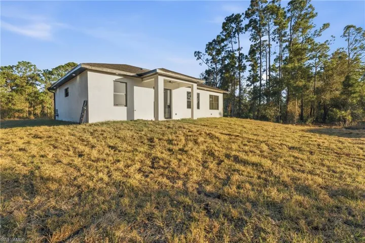 Rear view of property featuring stucco siding and a lawn
