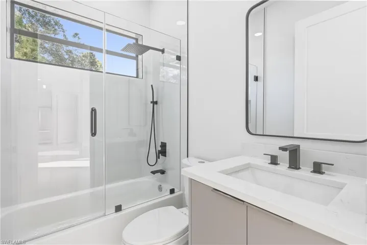 Full bathroom featuring vanity and bath / shower combo with glass door