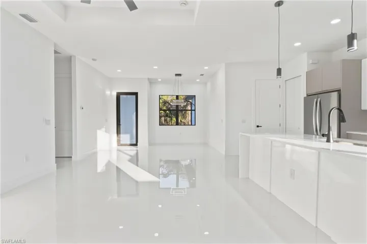 Kitchen featuring pendant lighting, modern cabinets, freestanding refrigerator, open floor plan, and light stone countertops