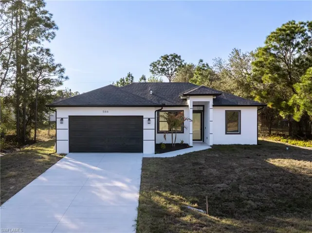 View of front facade with a front lawn, an attached garage, driveway, stucco siding, and a shingled roof