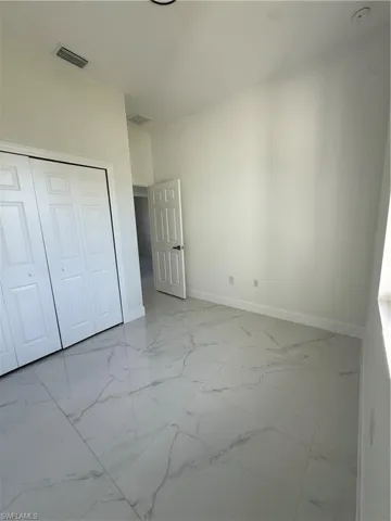 Unfurnished bedroom featuring light marble finish flooring and a closet
