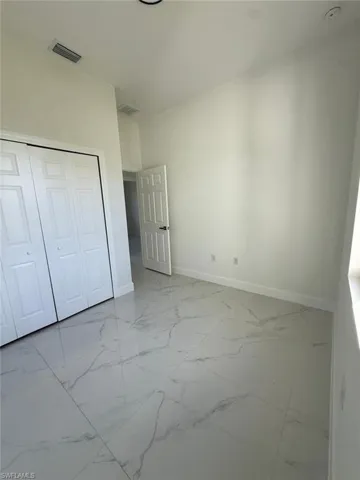 Unfurnished bedroom featuring light marble finish flooring and a closet
