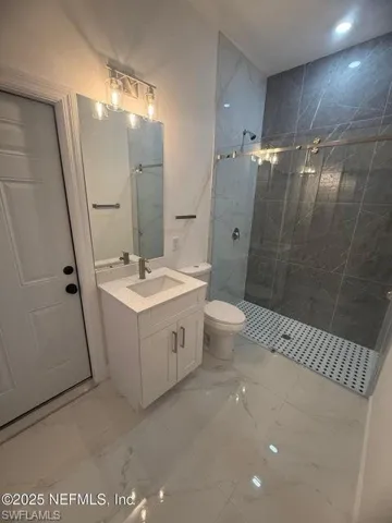 Full bathroom featuring a marble finish shower, vanity, light marble finish flooring, and recessed lighting