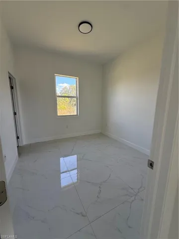 Spare room featuring light marble finish floors and baseboards