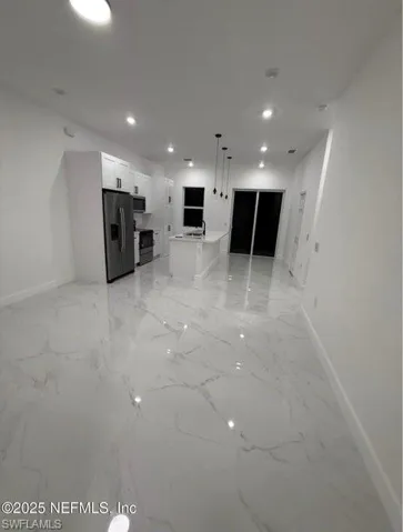 Unfurnished living room featuring light marble finish floors and recessed lighting