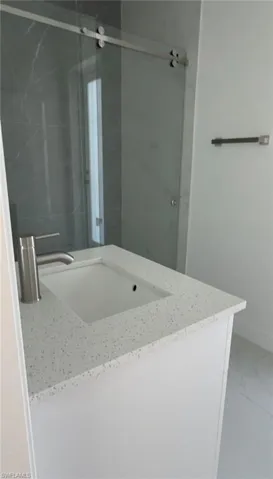 Full bath with vanity, marble look tiles, and a shower stall