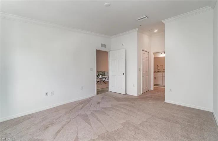 Unfurnished bedroom with ornamental molding, light colored carpet, and ensuite bath