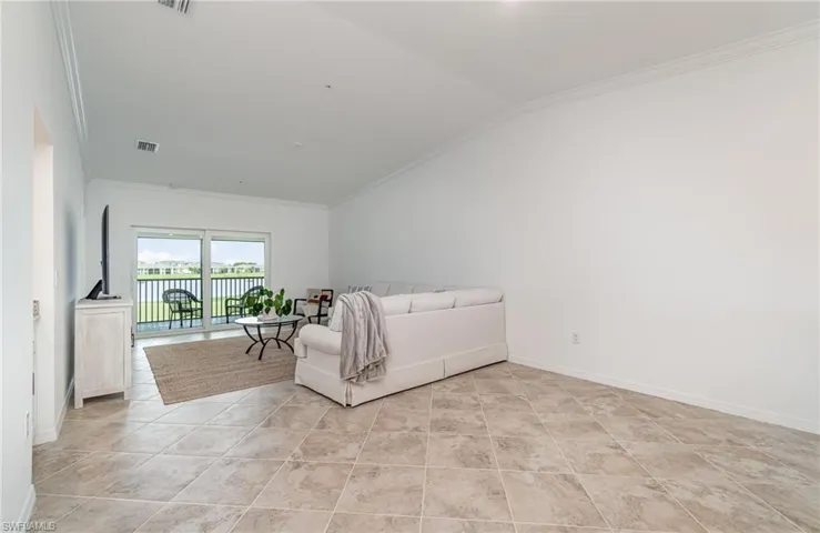 Tiled bedroom with vaulted ceiling, access to outside, and ornamental molding