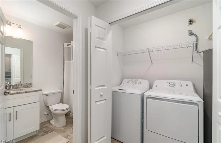 Laundry room featuring light tile patterned floors, sink, and washing machine and dryer
