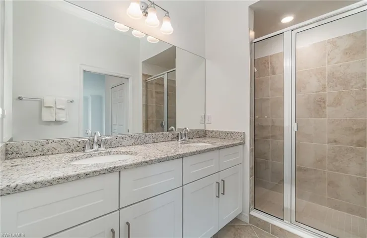 Bathroom featuring a shower with shower door, tile patterned flooring, and vanity