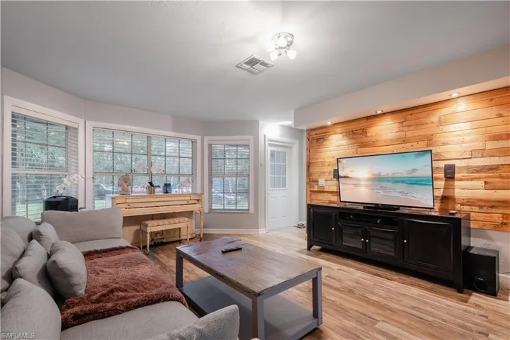 Living room with light wood-type flooring and wooden walls