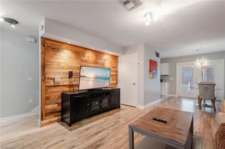 Living room with wood walls, light wood-type flooring, and a notable chandelier