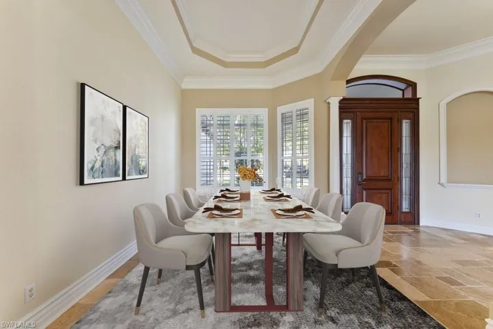 Dining space with crown molding, baseboards, ornate columns, and arched walkways