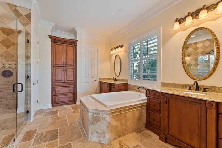 Full bathroom with crown molding, a garden tub, a sink, a stall shower, and stone tile flooring