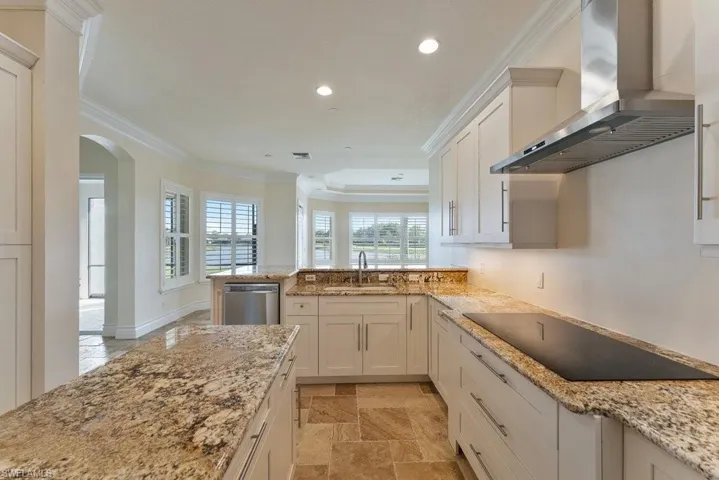 Kitchen with black electric cooktop, a sink, ornamental molding, wall chimney range hood, and stainless steel dishwasher
