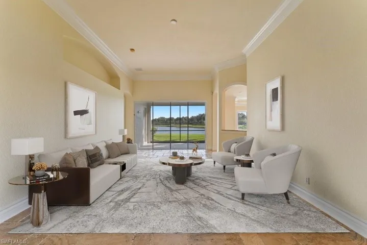 Living area featuring arched walkways, baseboards, and ornamental molding