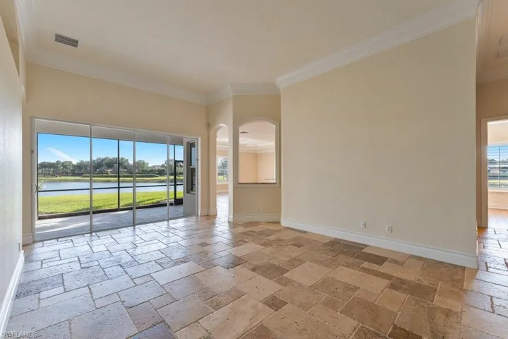 Empty room with baseboards, visible vents, stone tile floors, and ornamental molding
