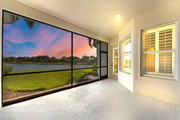 Unfurnished sunroom featuring a water view, vaulted ceiling, and a textured wall