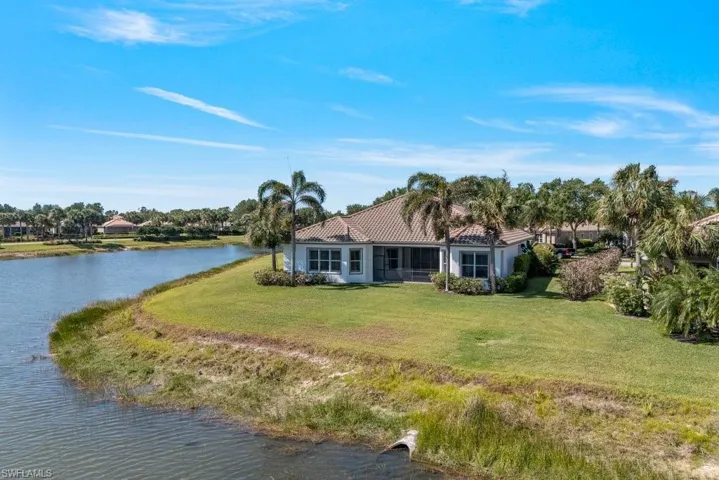 Rear view of property with a water view, a yard, stucco siding, and a tile roof