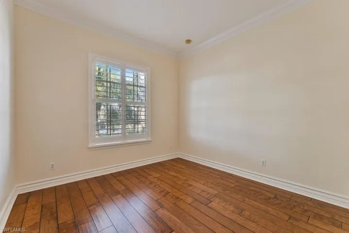 Unfurnished room with crown molding, baseboards, and hardwood / wood-style flooring