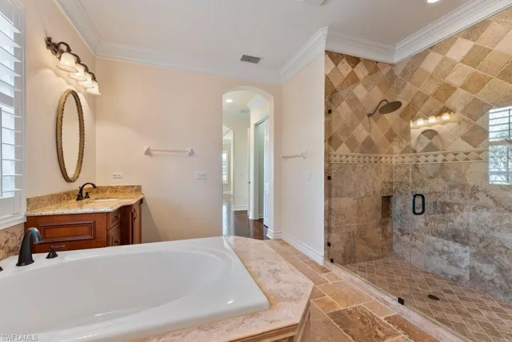 Bathroom featuring a bath, stone tile floors, ornamental molding, visible vents, and a stall shower