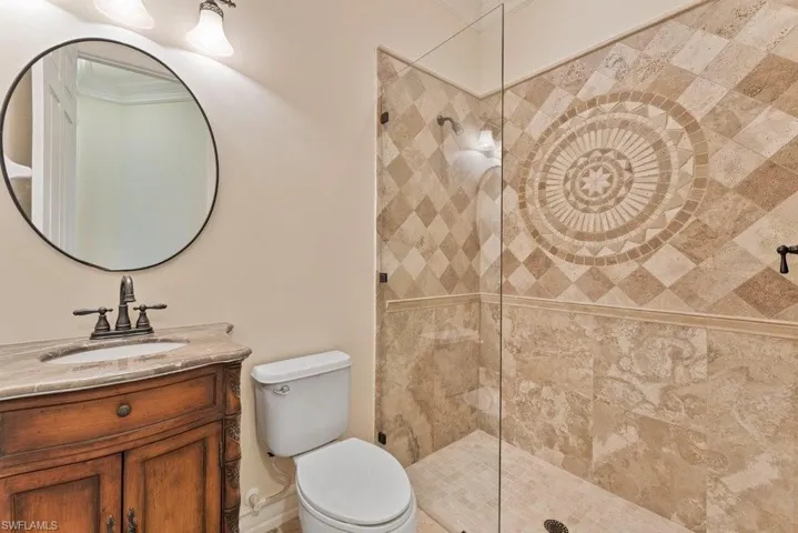 Bathroom with a tile shower, crown molding, vanity, and toilet