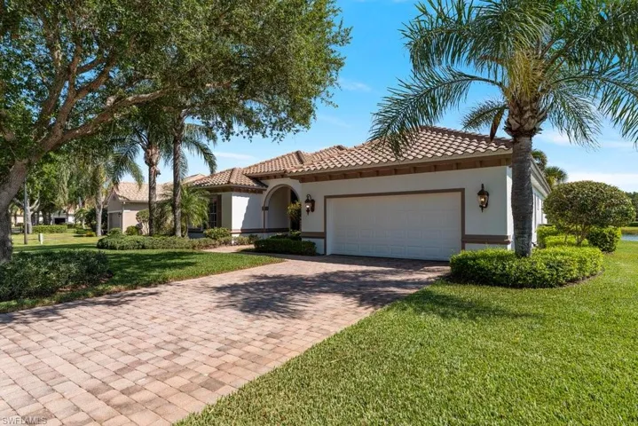 Mediterranean / spanish house with stucco siding, decorative driveway, an attached garage, a front lawn, and a tiled roof