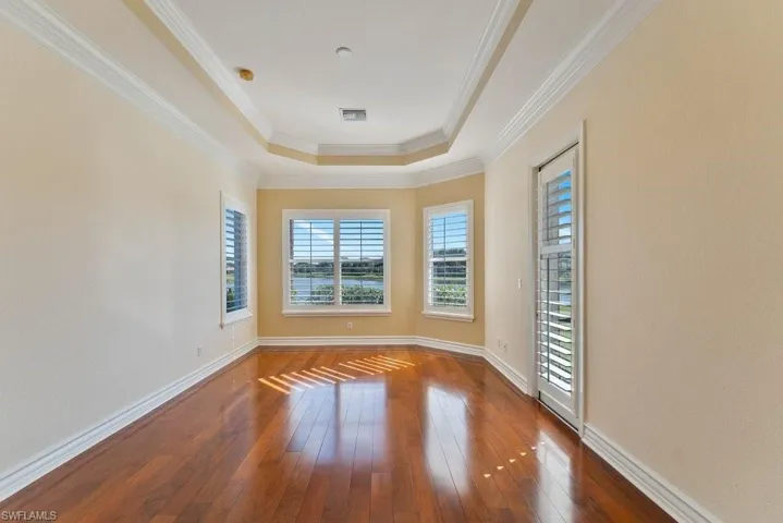 Spare room with baseboards, dark wood-style floors, crown molding, visible vents, and a raised ceiling