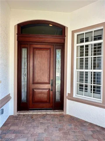 Entrance to property with covered porch and stucco siding