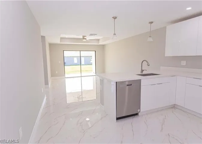 Modern kitchen featuring a white countertop island with an undermount sink and stainless steel dishwasher