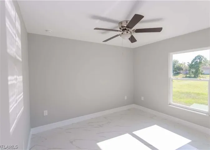 Bright room featuring a ceiling fan with integrated lighting, a large window, light gray walls, and white marble-look tile flooring
