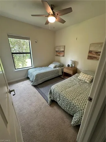 Carpeted bedroom with ceiling fan and baseboards