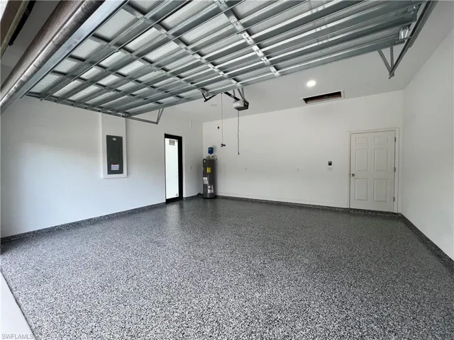 Garage featuring a garage door opener, electric water heater, and electric panel
