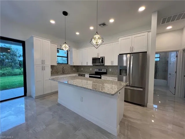 Kitchen with white cabinetry, a center island, stainless steel appliances, and sink