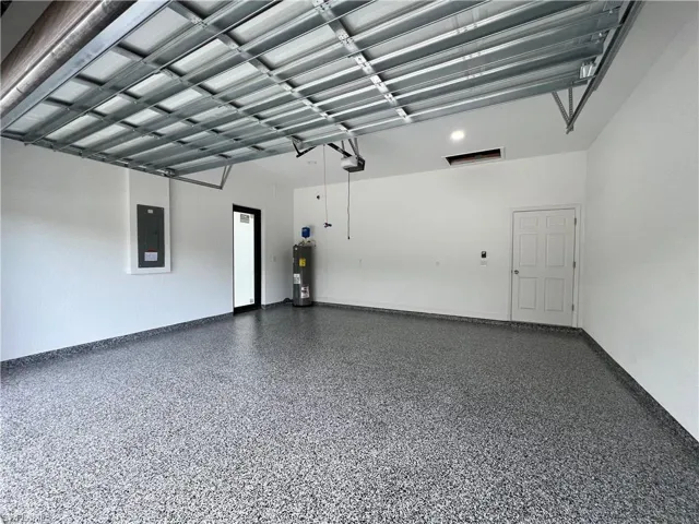 Garage with a garage door opener, water heater, and electric panel