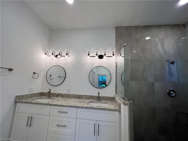 Bathroom featuring tiled shower and vanity