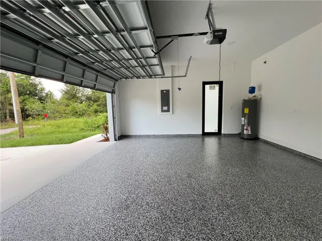 Garage with electric panel, a garage door opener, and water heater