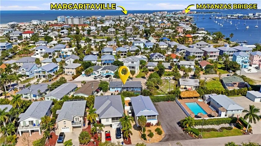 Aerial perspective highlighting a coastal neighborhood with numerous residential properties, abundant palm trees, and prominent water features
